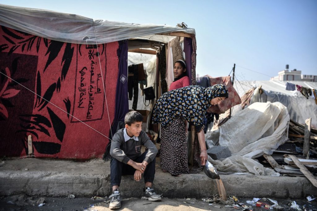 A Palestinian family sitting outside their tent in an IDP