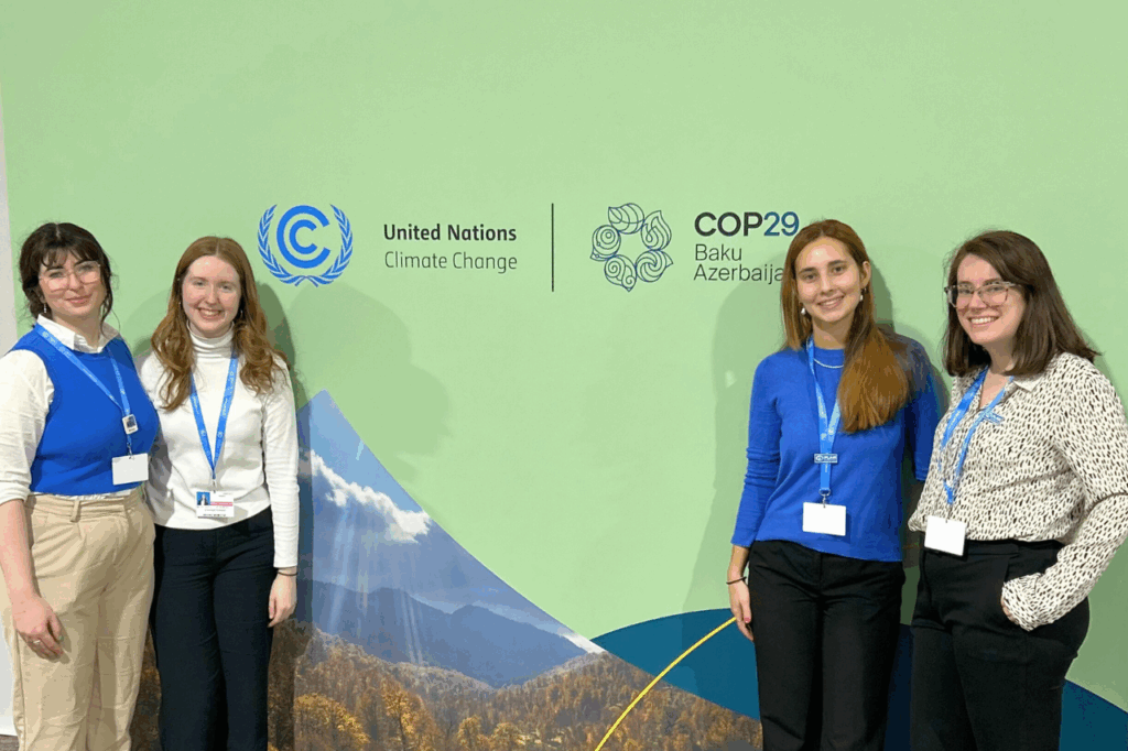 Four women standing in front of a backdrop where COP29 is written
