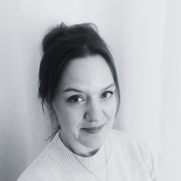 Alt text: Smiling woman with hair in updo and light sweater, grayscale portrait.