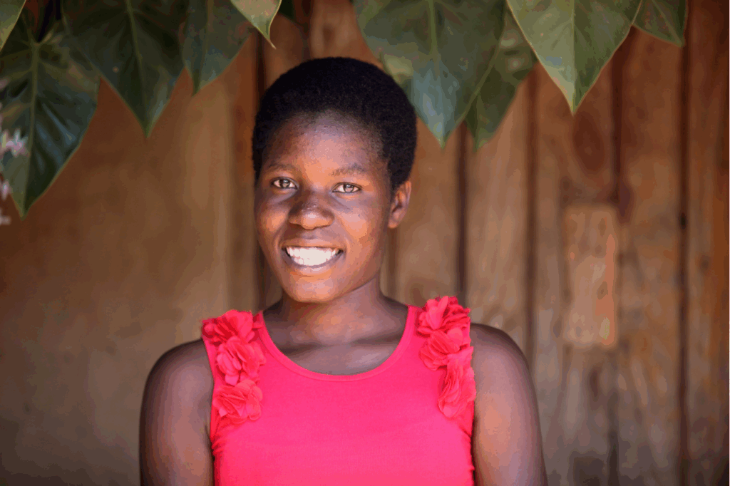 A girl in a pink top smiles at the camera